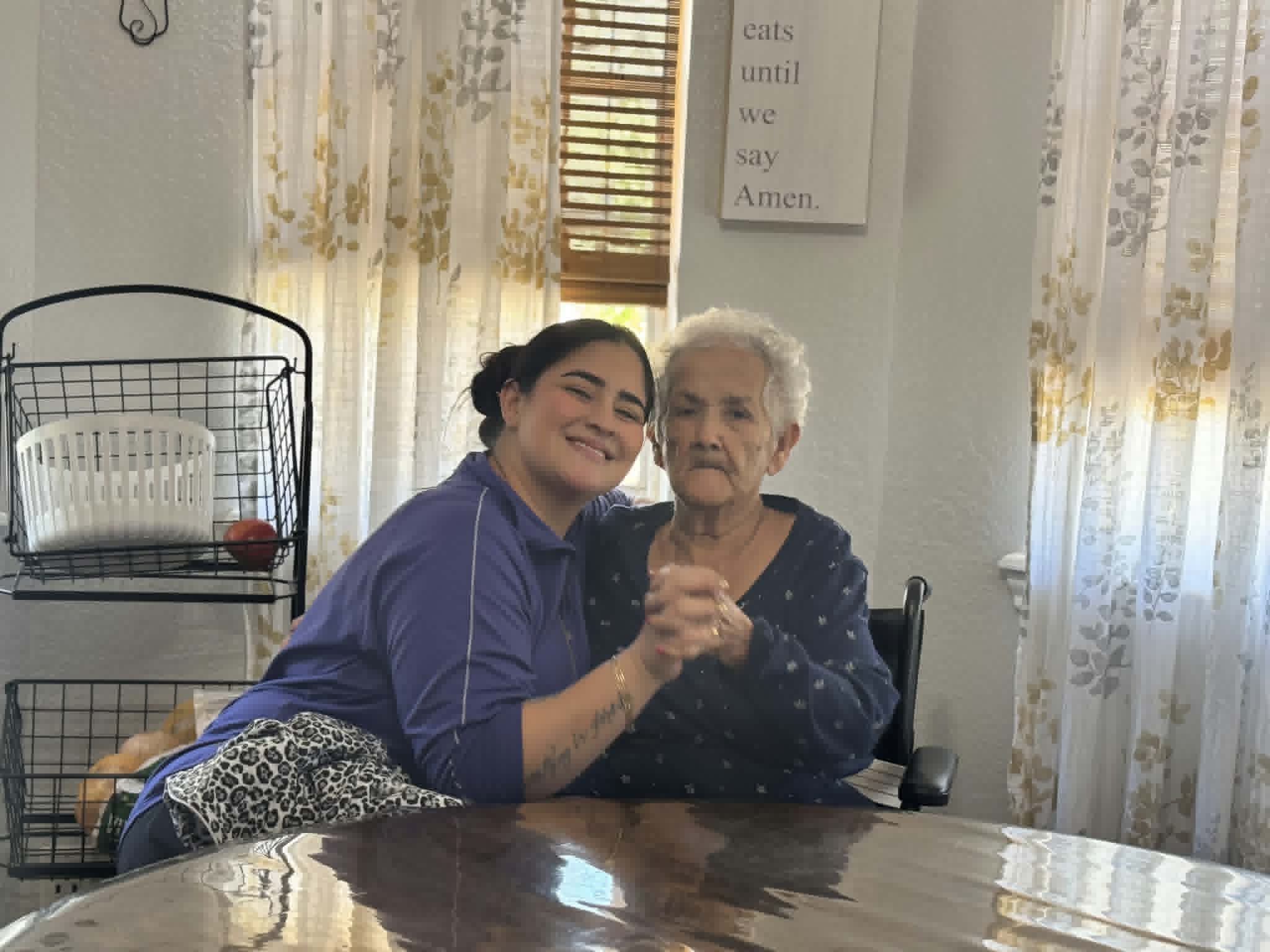 A caregiver gently holding hands with a resident at Nona's Place